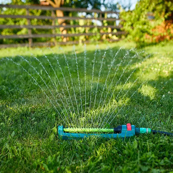 Oscillating-garden-sprinkler-spraying-water-over-green-grass